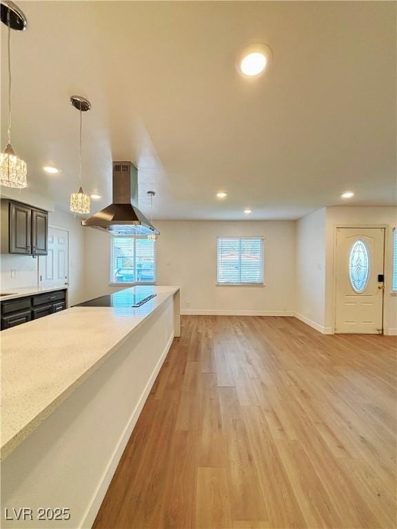 kitchen with light wood-style flooring, black electric cooktop, baseboards, ventilation hood, and decorative light fixtures