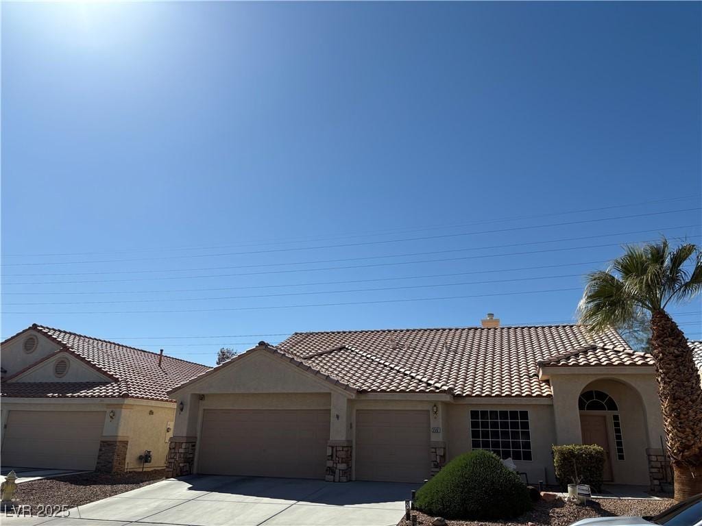 view of front facade featuring stucco siding, driveway, a tile roof, a garage, and a chimney