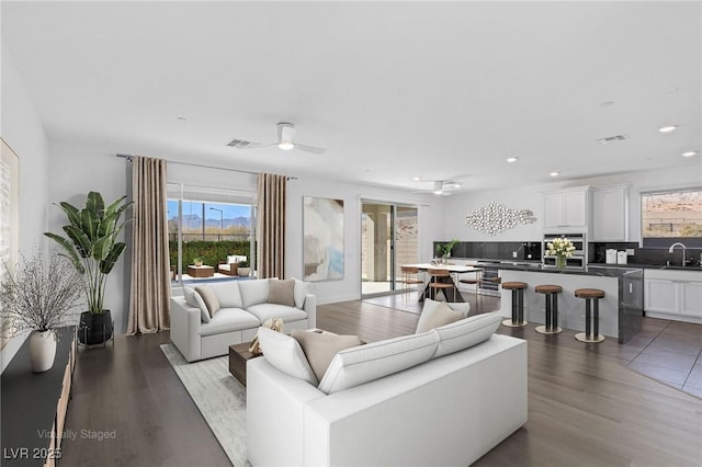 living room with wood finished floors, visible vents, and a ceiling fan