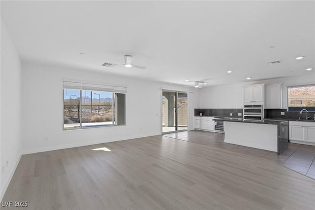 kitchen featuring open floor plan, visible vents, a sink, and backsplash