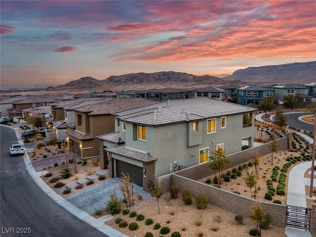 view of front of home with stucco siding, a mountain view, fence, a garage, and a residential view