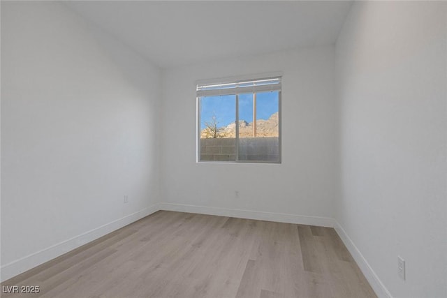 empty room featuring light wood finished floors and baseboards