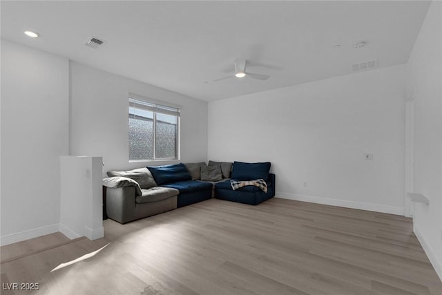 living room with light wood-style floors, baseboards, visible vents, and ceiling fan