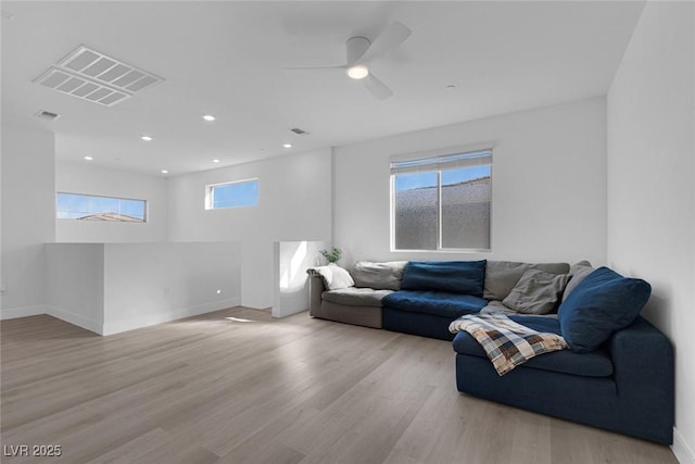 living area with wood finished floors, visible vents, and baseboards