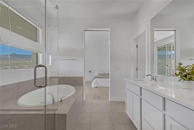 bathroom with baseboards, ensuite bathroom, tile patterned flooring, vanity, and a bath