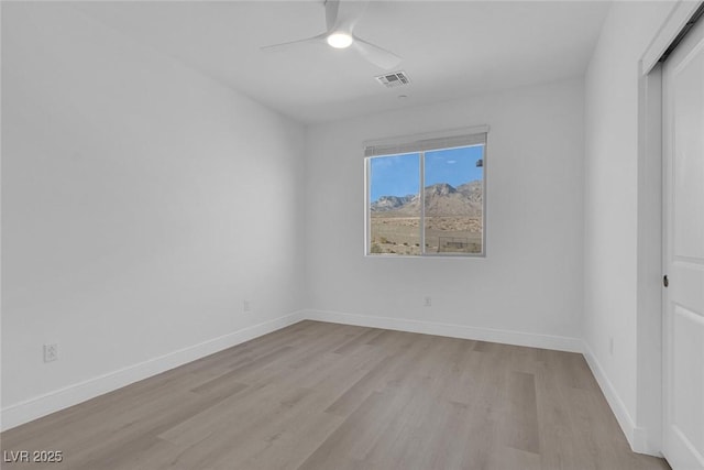 unfurnished room with light wood finished floors, ceiling fan, visible vents, and baseboards