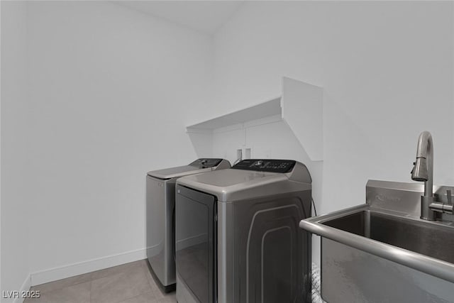 laundry room featuring light tile patterned flooring, laundry area, a sink, baseboards, and washer and clothes dryer