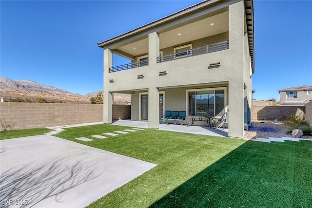 back of house with a yard, stucco siding, a patio area, a balcony, and a fenced backyard