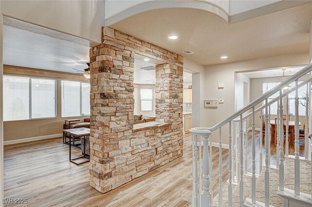 interior space with a ceiling fan, wood finished floors, visible vents, and baseboards