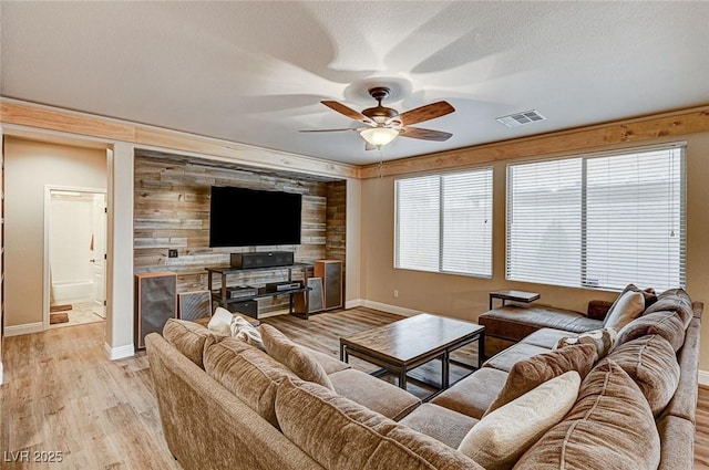 living room featuring visible vents, ceiling fan, a textured ceiling, light wood-type flooring, and baseboards