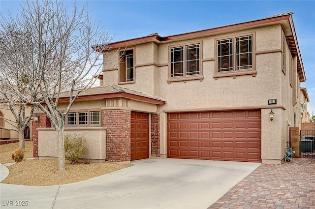 view of front of home with stucco siding, concrete driveway, central AC, fence, and a garage