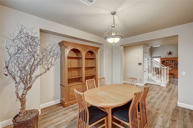 dining room featuring visible vents, light wood-style flooring, baseboards, and stairs