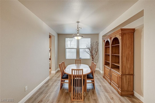 dining room featuring visible vents, a textured ceiling, light wood-style flooring, and baseboards