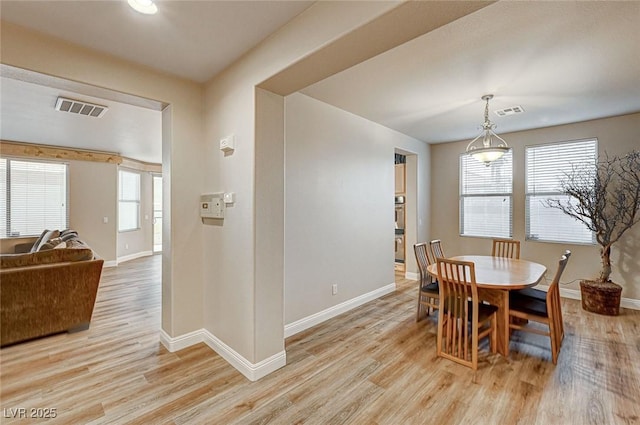 dining room with light wood-style flooring, visible vents, and a healthy amount of sunlight