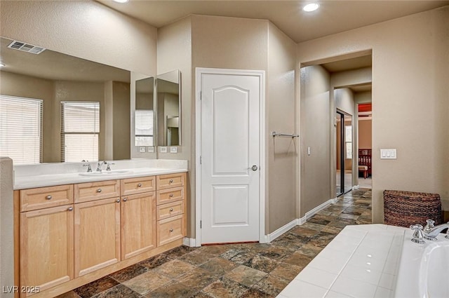 full bath with stone finish floor, a garden tub, visible vents, and vanity