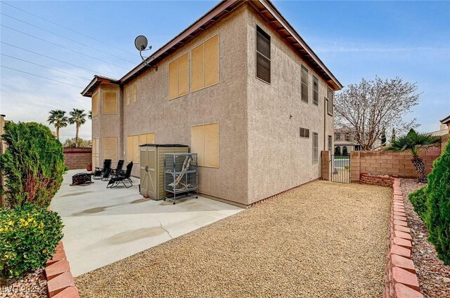 back of house featuring a patio, fence, a gate, and stucco siding