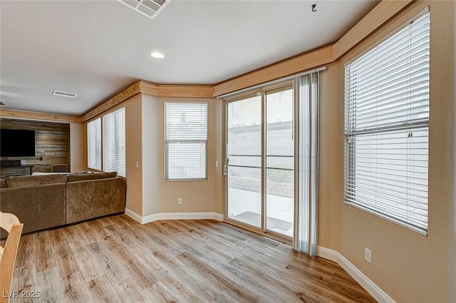 unfurnished living room featuring light wood finished floors, visible vents, and baseboards