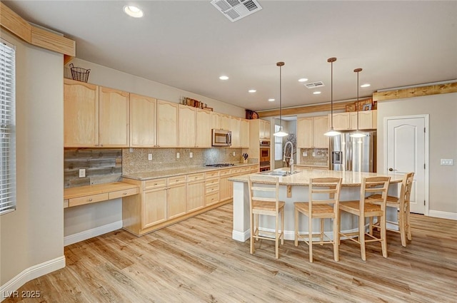 kitchen with appliances with stainless steel finishes, tasteful backsplash, visible vents, and light brown cabinetry