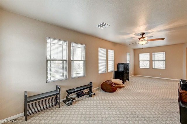 exercise room with a textured ceiling, ceiling fan, visible vents, baseboards, and carpet