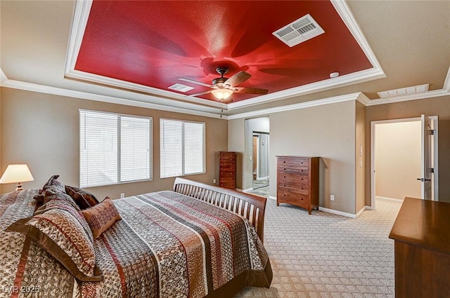 bedroom with a tray ceiling, visible vents, and light colored carpet