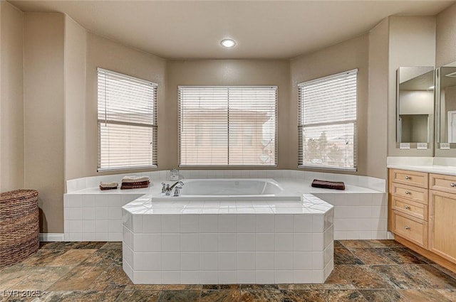 bathroom with a bath, stone tile flooring, and vanity