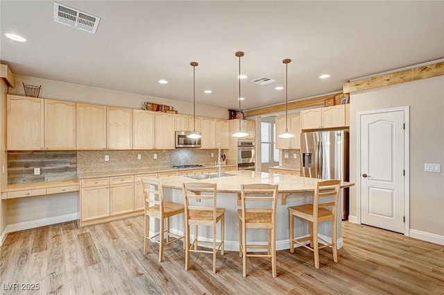 kitchen featuring stainless steel appliances, light brown cabinetry, a sink, and visible vents