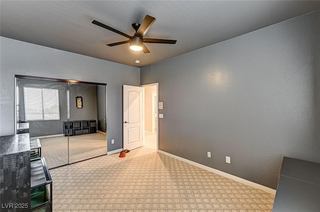 interior space with a textured wall, a closet, ceiling fan, and baseboards