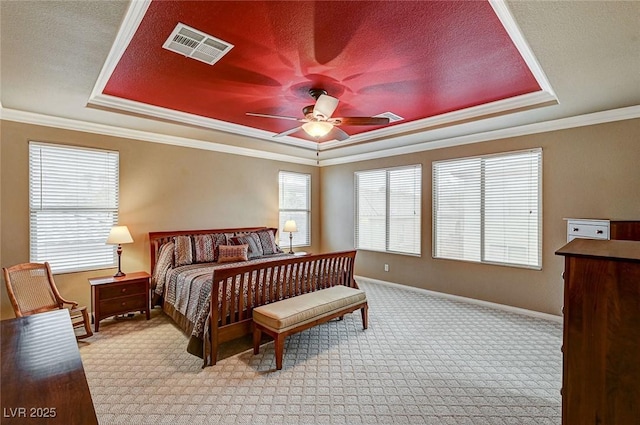 bedroom featuring a textured ceiling, light colored carpet, visible vents, baseboards, and a tray ceiling