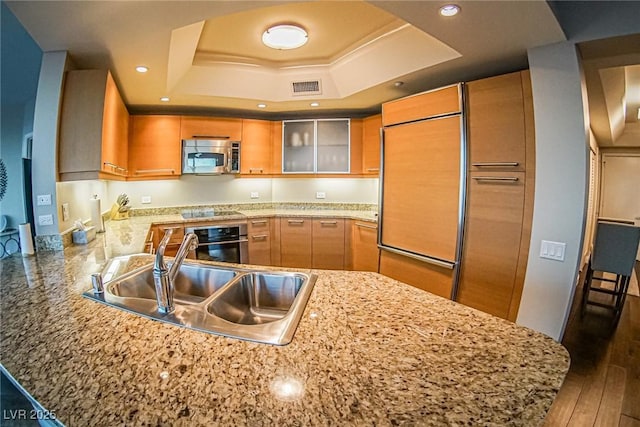 kitchen featuring a peninsula, a sink, visible vents, appliances with stainless steel finishes, and a raised ceiling