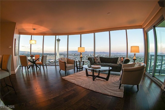 living room with dark wood-style floors, plenty of natural light, and a wall of windows