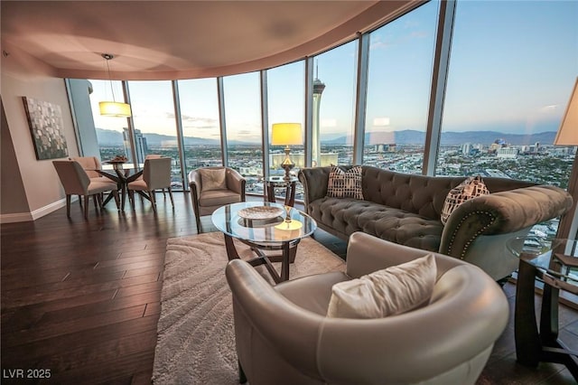 living room with expansive windows, a view of city, baseboards, and dark wood finished floors