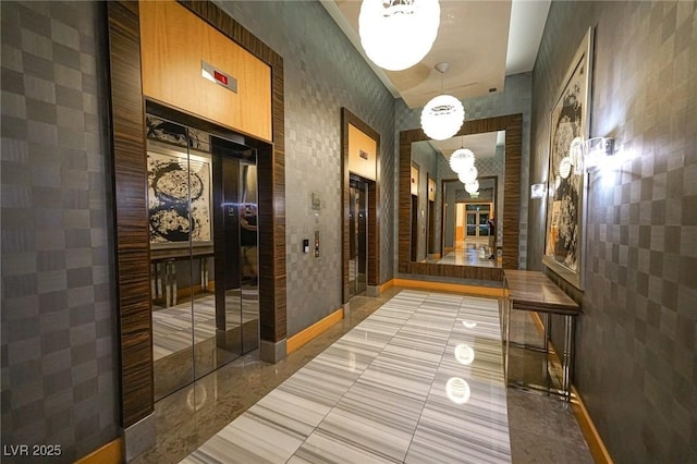 hall featuring elevator, baseboards, and light tile patterned floors