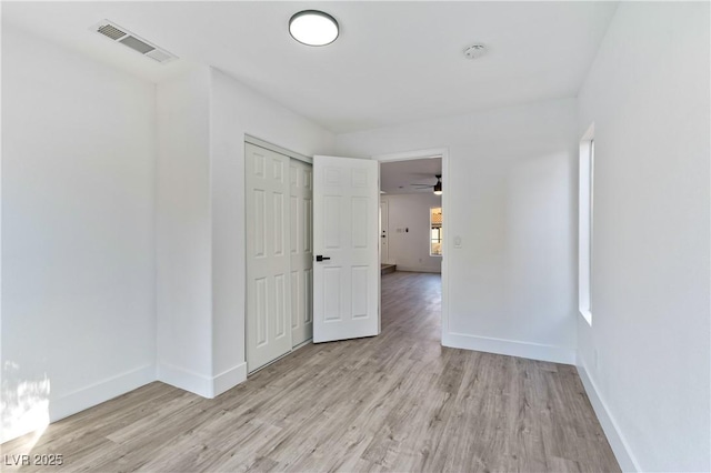 unfurnished room with light wood-type flooring, visible vents, and baseboards