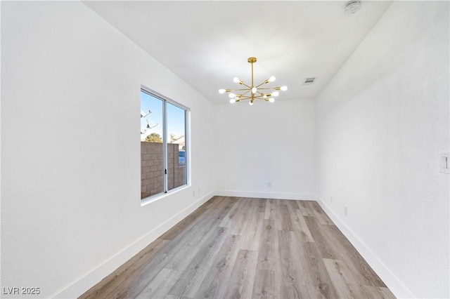 empty room with baseboards, light wood-type flooring, visible vents, and an inviting chandelier