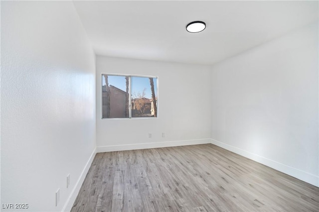 spare room with baseboards and wood finished floors