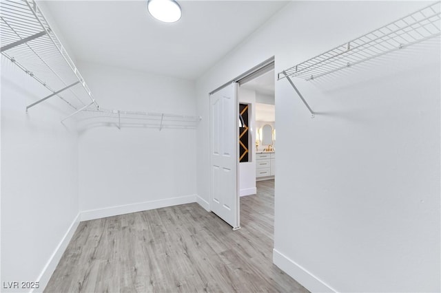 spacious closet with a barn door and wood finished floors