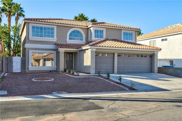 mediterranean / spanish home featuring driveway, fence, and stucco siding