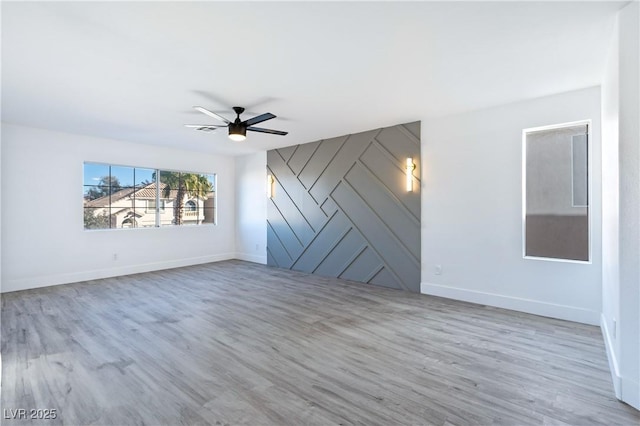 empty room with ceiling fan, baseboards, and wood finished floors