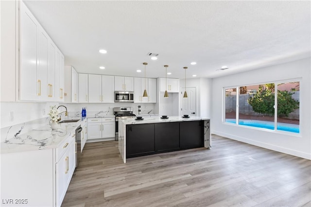 kitchen with a center island, stainless steel appliances, recessed lighting, white cabinets, and light wood-type flooring