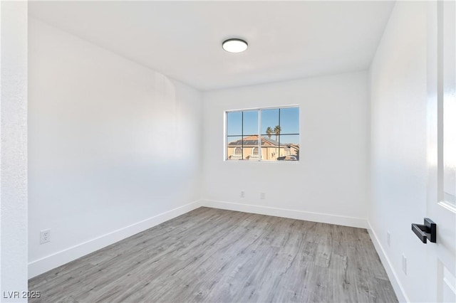 spare room with baseboards and wood finished floors