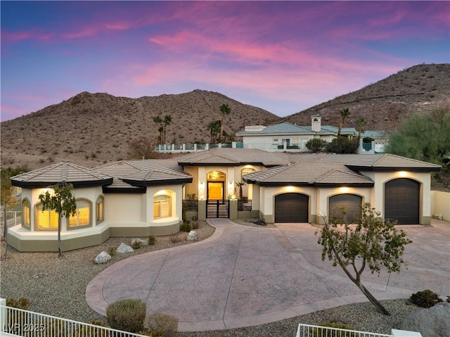 mediterranean / spanish home with an attached garage, fence, a mountain view, and concrete driveway