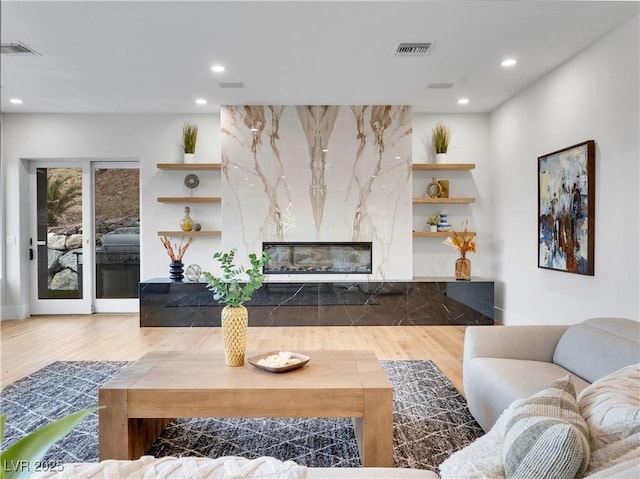 living area featuring a premium fireplace, visible vents, wood finished floors, and recessed lighting