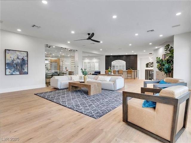 living room featuring light wood-type flooring, baseboards, visible vents, and recessed lighting