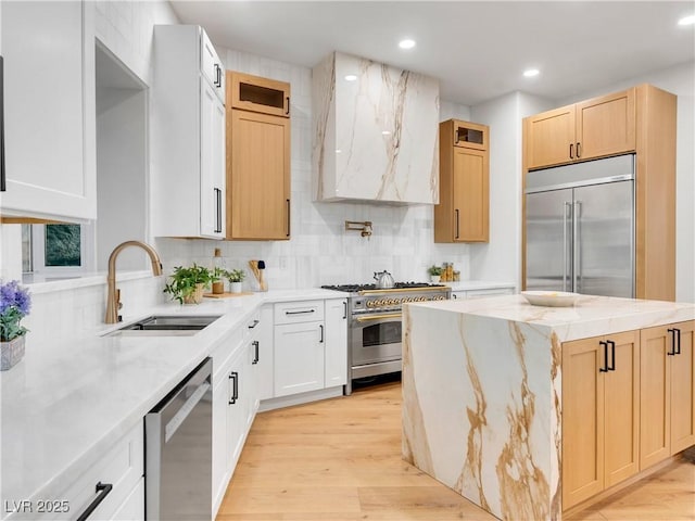 kitchen featuring high quality appliances, light stone counters, a center island, custom exhaust hood, and a sink