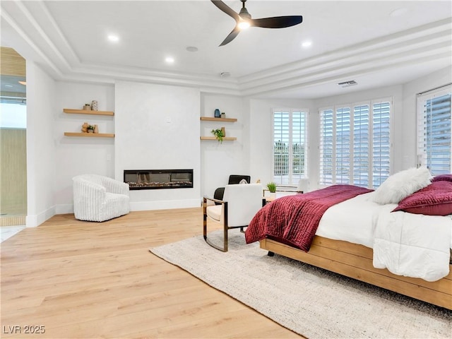 bedroom with recessed lighting, visible vents, a glass covered fireplace, wood finished floors, and baseboards