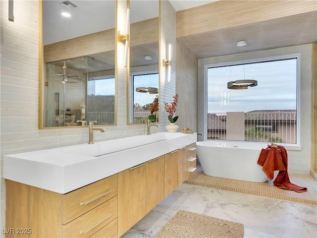 full bathroom with marble finish floor, tile walls, a soaking tub, visible vents, and a shower with shower door