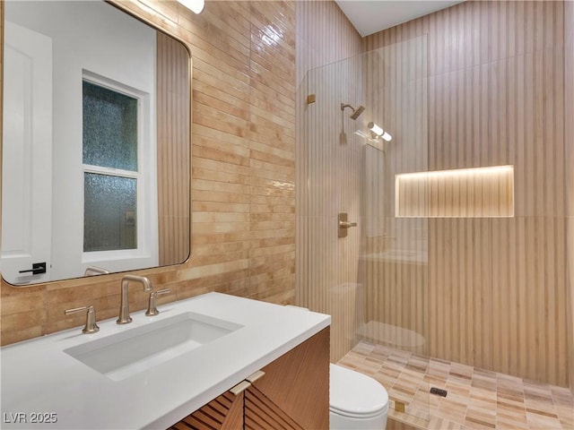 bathroom featuring tiled shower, tile walls, toilet, and vanity