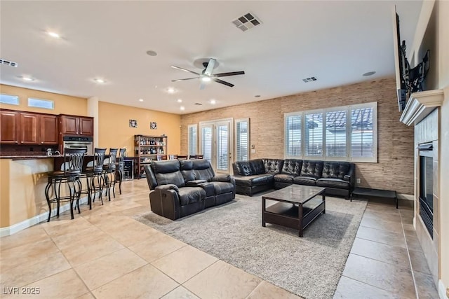 living room featuring light tile patterned floors, recessed lighting, visible vents, and a glass covered fireplace