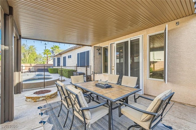 view of patio / terrace featuring an outdoor fire pit, an outdoor hot tub, fence, and outdoor dining space