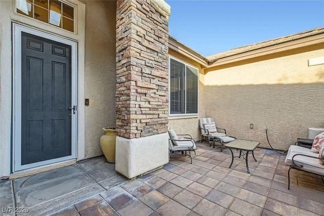 view of exterior entry with a patio and stucco siding